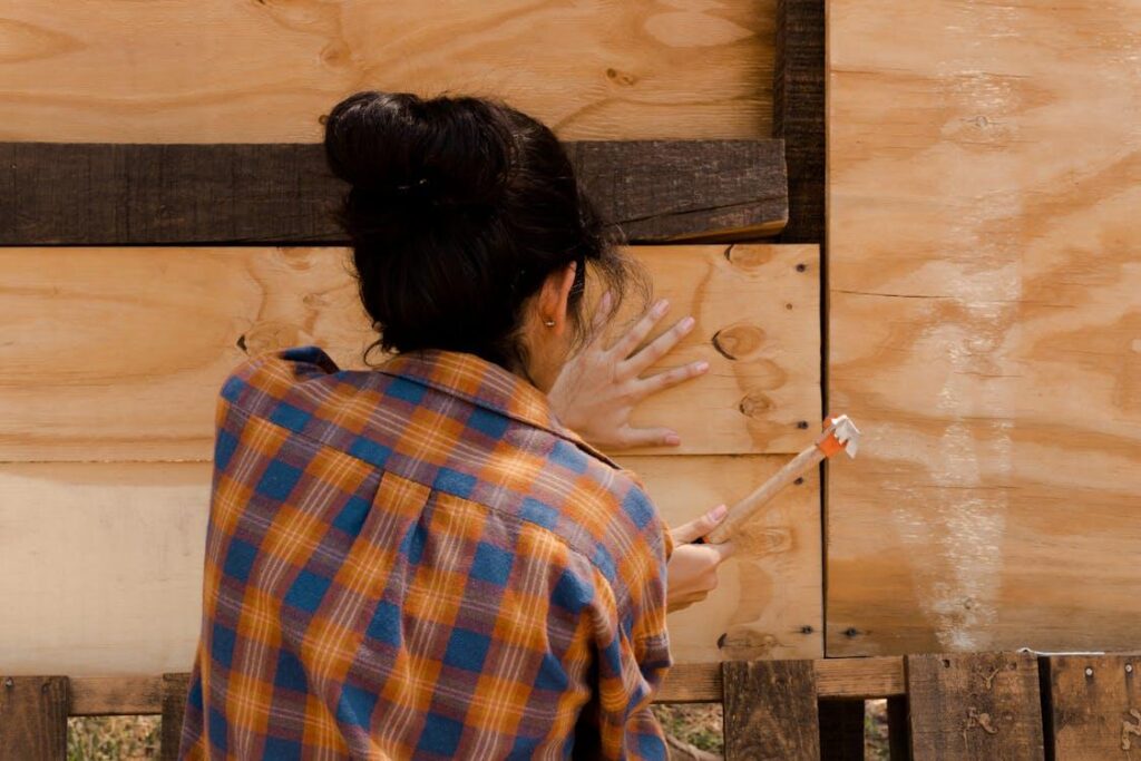 A woman hammering a fence