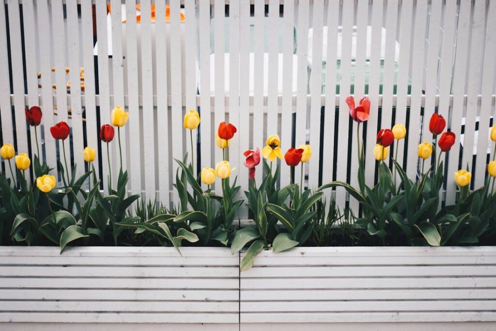 A well-maintained wooden fence lined with blooming flowers enhancing a thoughtfully designed yard.