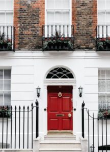 Elegant wrought iron fence representing fence styles in Camden County in front of a townhouse with a red front door.