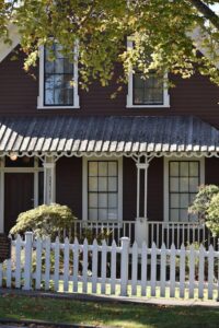 White picket fence showcasing residential fencing in Cherry Hill, NJ, around a traditional home with a shaded front yard.