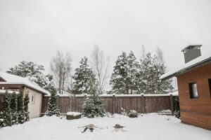 a house surrounded by a wooden fence in snow