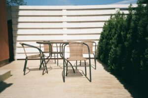 A table and chairs near a white fence 