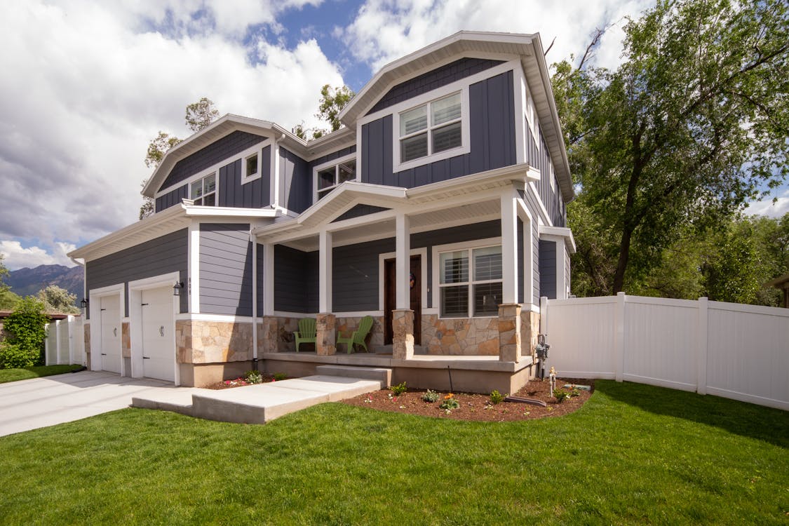 a two-story house with a white fence during the daytime
