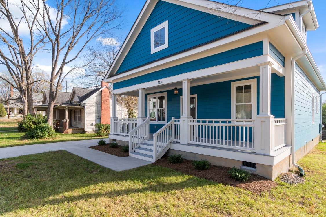 photo of a blue house with a white fence in front
